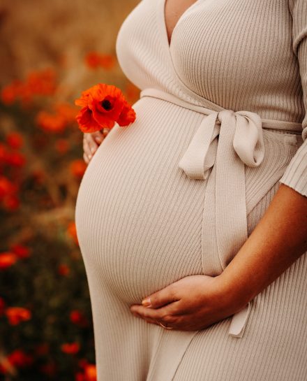 A pregnant female standing among blooming poppy field